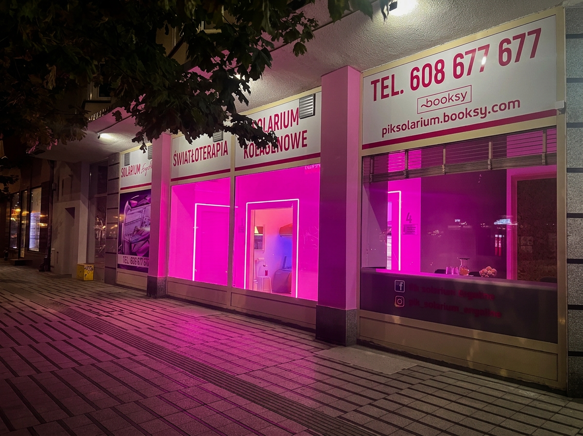 Witryna salonu PIK Solarium w Poznaniu rozświetlona różowym neonem nocą